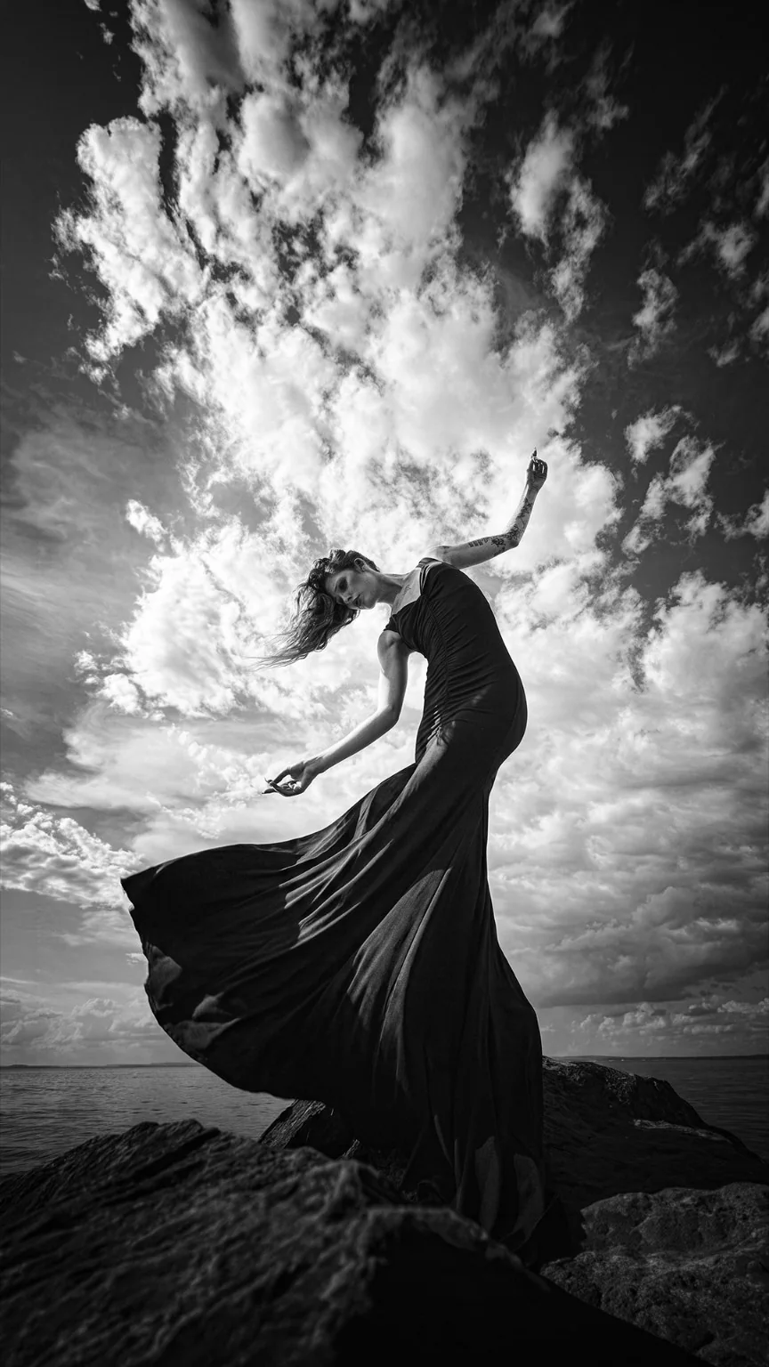 Black and white fine art photograph, flowing dress under dramatic clouds